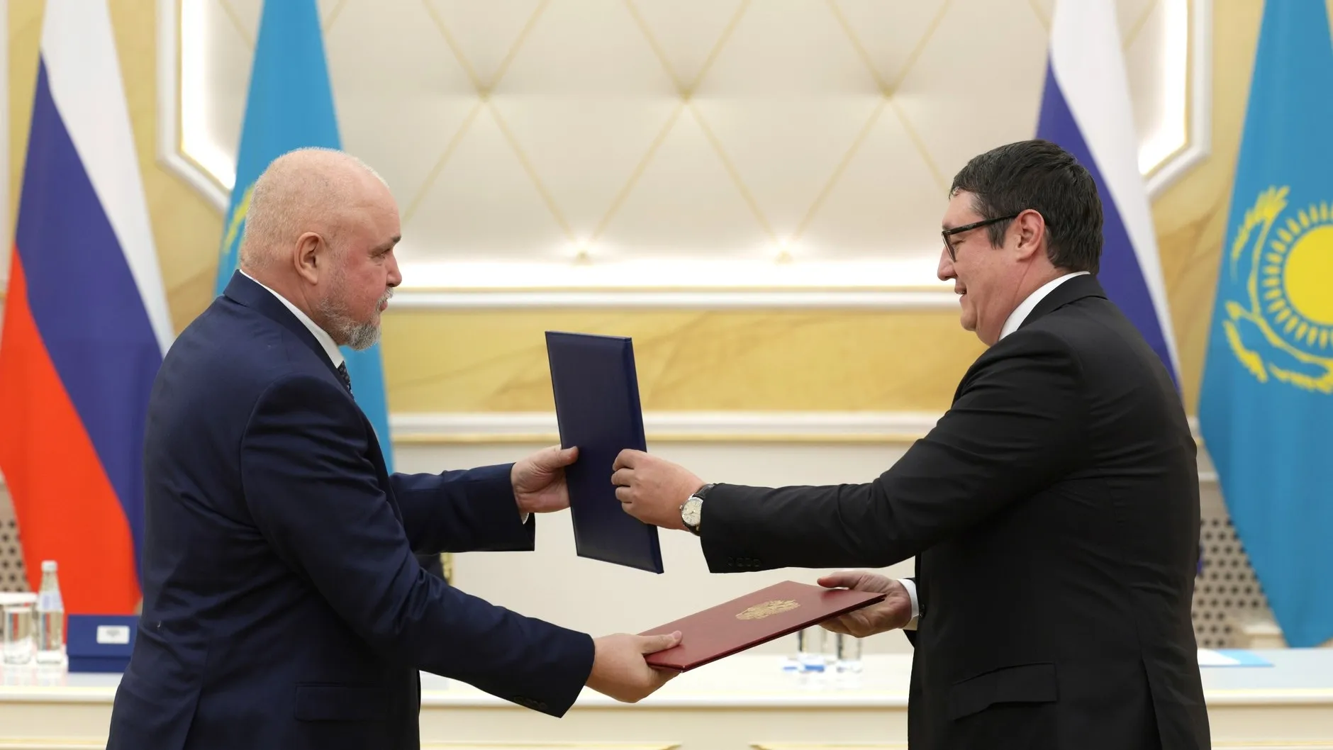 Ziwiljow (links) und Almassadam Satkalijew tauschen die Dokumente aus, 27. November 2024. Foto: kremlin.ru, CC BY